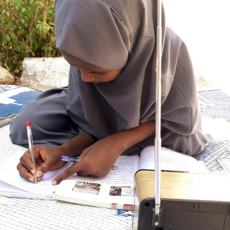 منى عبد الرحمن محمد، طالبة في الصف الثامن، تستمع باهتمام إلى الدروس التي تبثها الإذاعة في الصومال.