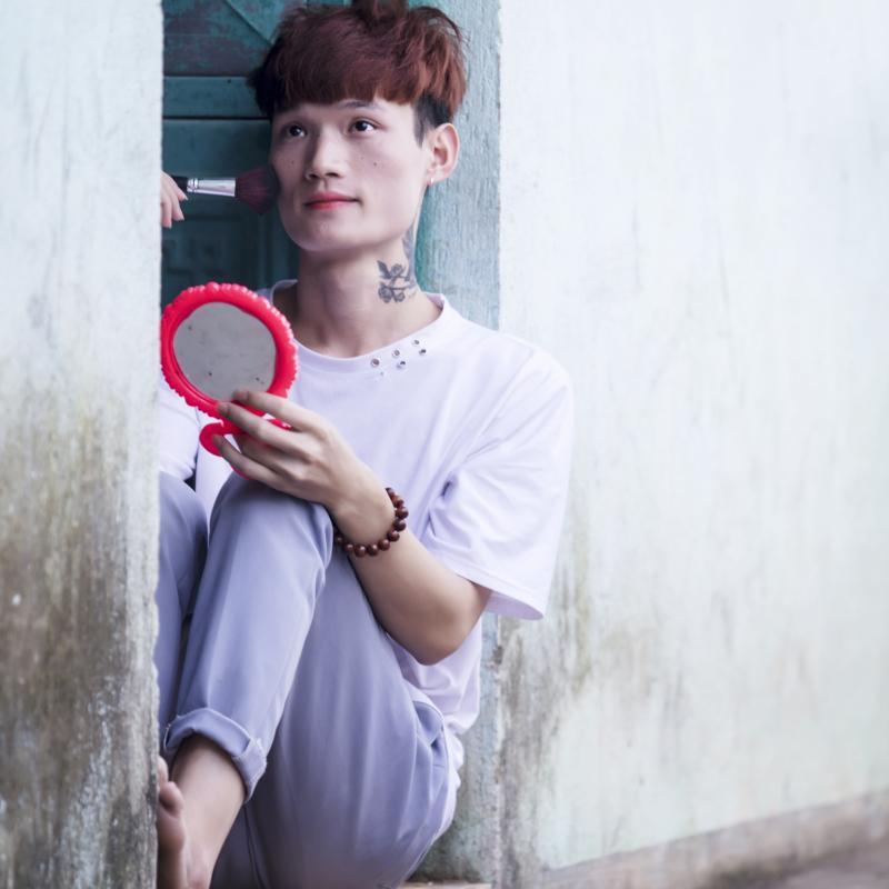 Bui Thi Chi se sienta agachada en una puerta mientras se maquilla.